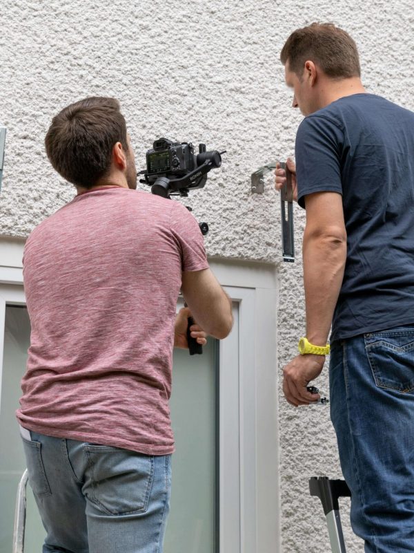 Ein Handwerker wird bei der Montage eines Bügels auf einer Leiter von Bastian gefilmt.